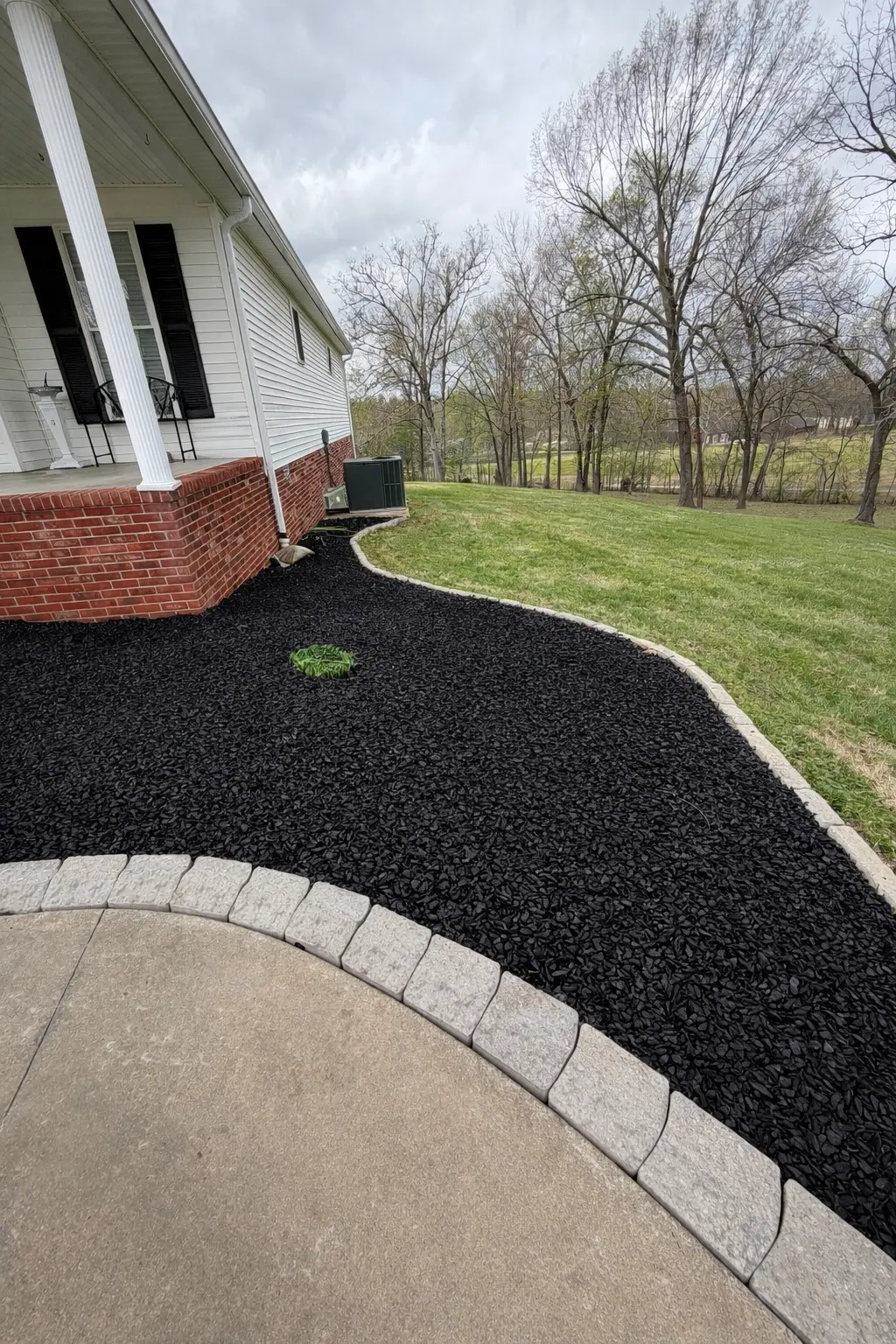 Black mulch bed with light gray paver edging installed by Luxury Lawns